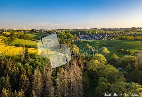 Image of Drone flies over countryside with green field.