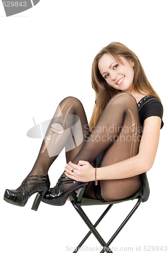 Image of Smiling pretty girl in the torn stockings sits on a chair