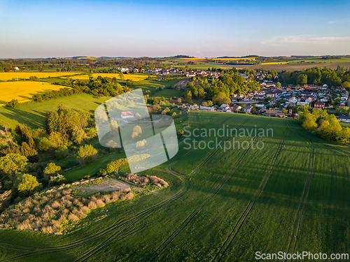 Image of Drone flies over countryside with green field.