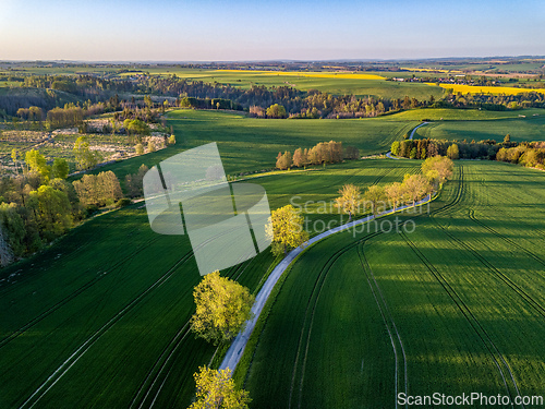 Image of Drone flies over countryside with green field.