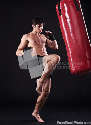 Image of Man, athlete and boxing bag with kick in studio for self defence fighter, martial arts or black background. Male person, wellness and mockup space for strength training with gym, fitness or sport