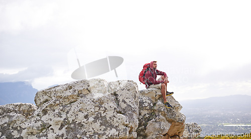 Image of Man, mountain and relax on outdoor hike in nature, workout and peace or calm on rocks for wellness. Male person, exercise and travel with backpack on vacation, adventure and explore bush for fitness