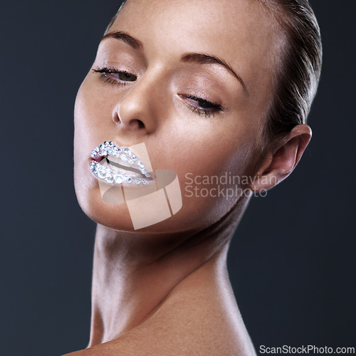 Image of Beauty, face and woman with crystal on lips in studio with jewelry isolated on black background. Diamond, sparkle and model with creative makeup for skincare, cosmetics or art for aesthetic lipstick