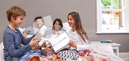 Image of Excited kids, parents and bed with gifts for Christmas, birthday or surprise together at home. Happy children or siblings opening presents, boxes or celebration in bedroom with mom and dad at house