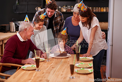 Image of Family, birthday cake and happy kid with mom, dad and grandparents together with people and candles. Youth, smile and dessert with children and celebration with event food and party hats at a table