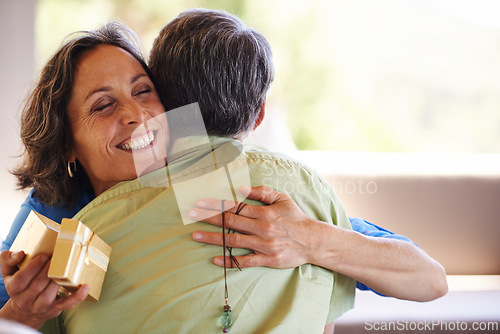 Image of Love, hug and mature couple with gift for birthday, valentines day or anniversary celebration. Gratitude, romance and happy man giving woman a box, present or surprise for romantic gesture in house