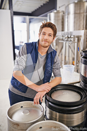 Image of Brewery, man and container machine with portrait for craft beer, manufacturing or production process in factory. Industrial industry, worker and smile in distillery with tank for brewing in warehouse