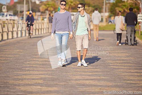 Image of Couple, gay and men with holding hands for walk, sunglasses and summer on promenade. Male people, honeymoon and strolling for beach vacation with partners, supportive and together in Cape Town