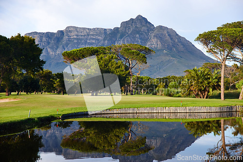 Image of Golf course, lake and mountain with trees of outdoor nature, scenery or sports ground. Empty field, green grass and view of natural elements with water, forest or colorful turf for park or wilderness