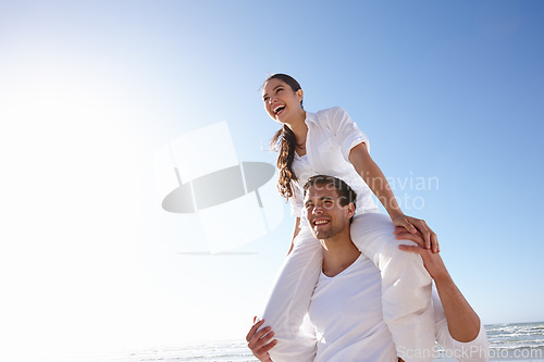 Image of Happy, couple and beach with piggyback and blue sky for valentines day, love or summer holiday together in embrace or outdoor romance. Man and woman with smile by ocean in nature on mockup space