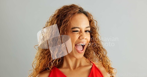 Image of Happy woman person, wink and laughing in studio, excited and flirt on grey background. Cheerful, joyful and smile on female model face, friendly and natural with curly hair of fun African Lady