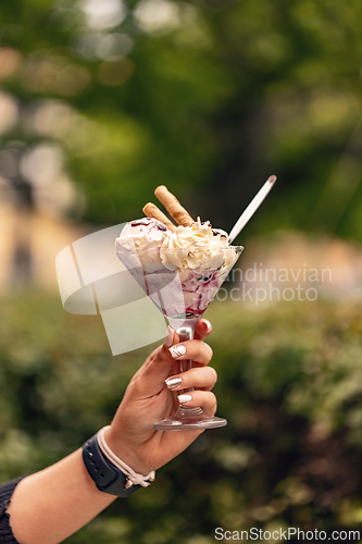 Image of Woman is holding a glass cup of ice cream