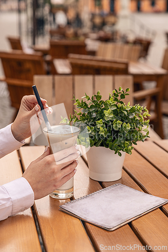 Image of Businesswoman in a white shirt is holding an iced coffee latte