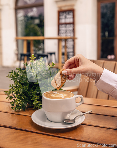 Image of Woman dipping biscuit in cappuccino