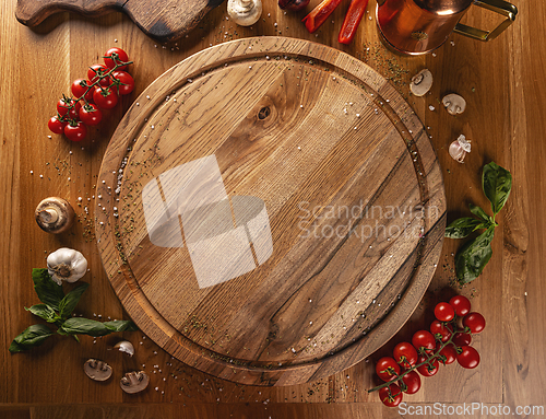 Image of Empty wooden cutting board surrounded by vegetables and spices