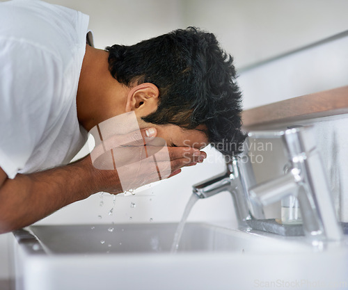 Image of Water, wash and man in bathroom for hygiene, grooming and cleaning face at home, house or apartment. Male person, gen z guy and student by tap, basin or cleansing for skincare, dermatology or beauty