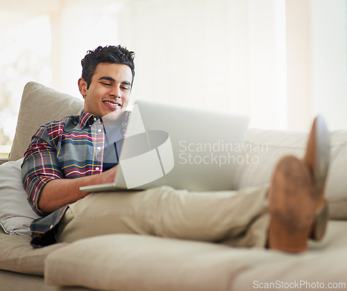 Image of Man, laptop and home for internet connection with streaming service for free time, stress relief or resting. Male person, smile and couch with technology for online subscription, watching or blogging