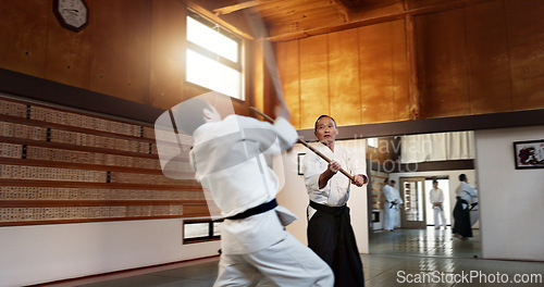 Image of Aikido men, fight and bokken for martial arts, weapon or contest for black belt students at training, gym or dojo. Japanese people, wood sword and sensei for exercise, workout and fitness in battle