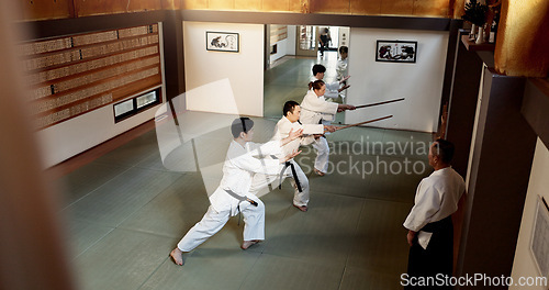 Image of Aikido students, stick or learning martial arts in dojo for practice, movement or self defense. Combat demonstration, above or Japanese people in training workout for fighting, education or sensei