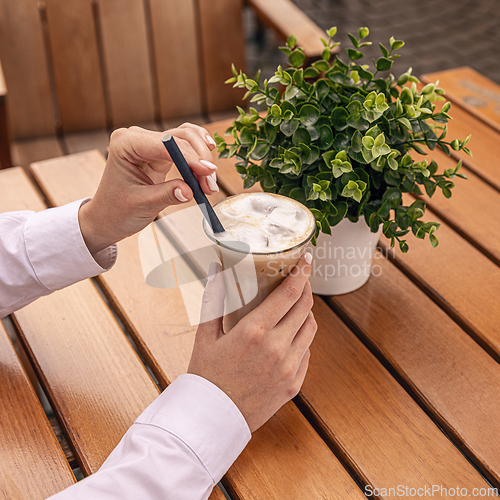 Image of Businesswoman holding iced coffee latte
