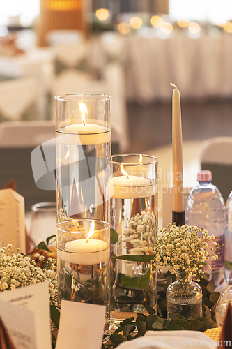 Image of Soft lit candles in glass vases with flowers