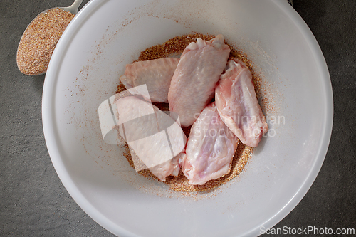 Image of fresh raw chicken wings in bowl of spices