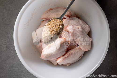 Image of fresh raw chicken wings in bowl of spices