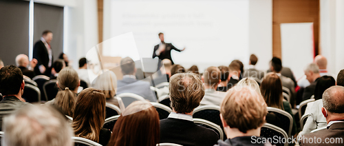 Image of Speaker giving a talk in conference hall at business event. Rear view of unrecognizable people in audience at the conference hall. Business and entrepreneurship concept.
