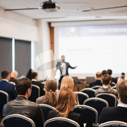 Image of Speaker giving a talk in conference hall at business event. Rear view of unrecognizable people in audience at the conference hall. Business and entrepreneurship concept.