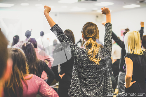 Image of Participants of interactive motivational speech feeling empowered and motivated, hands raised high in the air.