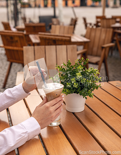 Image of Woman holding glass with iced coffee