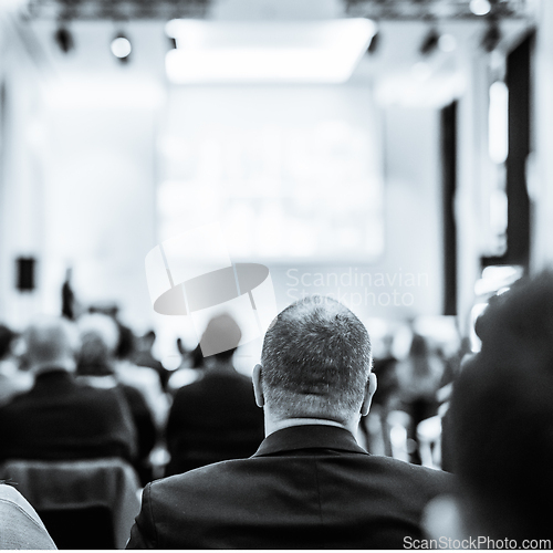 Image of Speaker giving a talk in conference hall at business event. Rear view of unrecognizable people in audience at conference hall. Business and entrepreneurship concept. Black and white selenium image