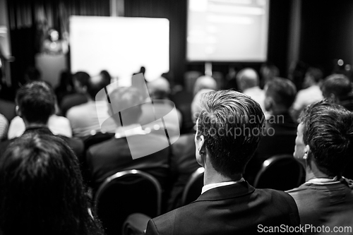 Image of Speaker giving a talk in conference hall at business event. Rear view of unrecognizable people in audience at the conference hall. Business and entrepreneurship concept.