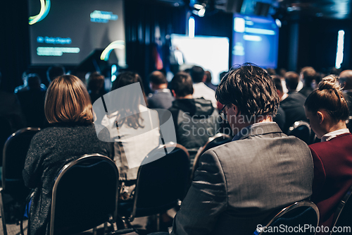 Image of Speaker giving a talk in conference hall at business event. Rear view of unrecognizable people in audience at the conference hall. Business and entrepreneurship concept.