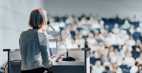 Image of Female speaker giving a talk on corporate business conference. Unrecognizable people in audience at conference hall. Business and Entrepreneurship event.