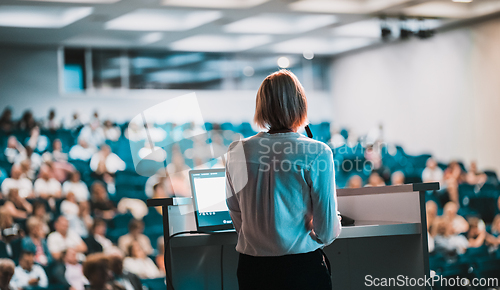 Image of Female speaker giving a talk on corporate business conference. Unrecognizable people in audience at conference hall. Business and Entrepreneurship event.