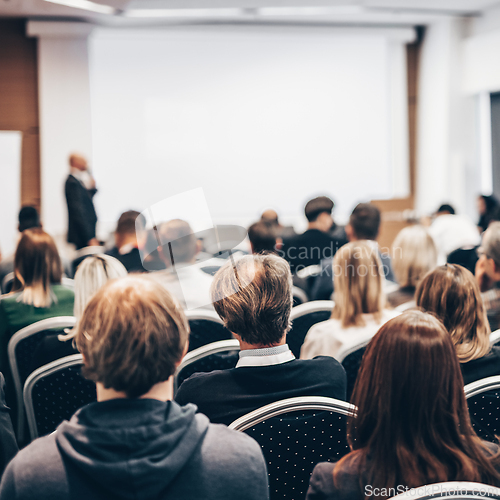 Image of Speaker giving a talk in conference hall at business event. Rear view of unrecognizable people in audience at the conference hall. Business and entrepreneurship concept.