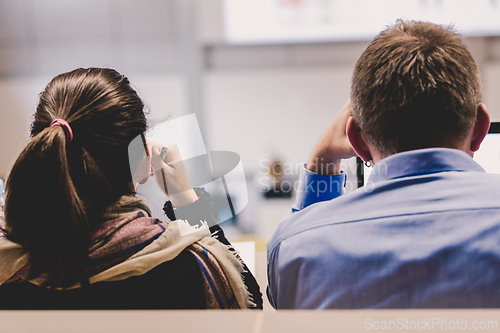 Image of Students listening to lecture and making notes. Professor giving presentation in lecture hall at university