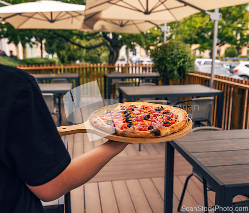 Image of Waiter carrying a freshly baked pizza