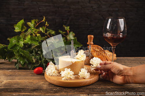 Image of Woman slicing delicious tete de moine cheese