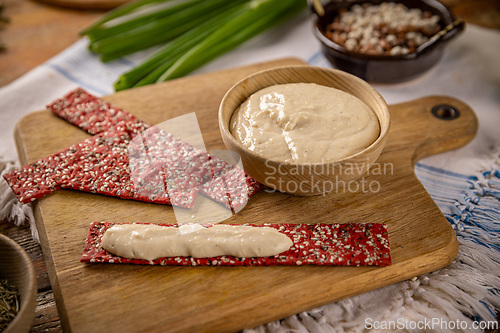 Image of Bowl of hummus with red beetroot crackers