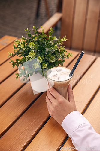 Image of Businesswoman holding iced coffee latte