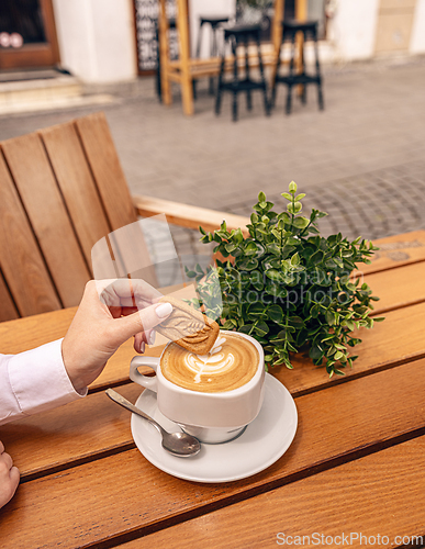Image of Woman dipping a biscuit into her cappuccino