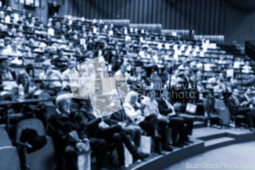 Image of Blurred, unrecognizable, business people in the audience listening to lecture in conference hall. Business and Entrepreneurship concept. Blue toned monochrome image