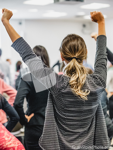 Image of Participants of interactive motivational speech feeling empowered and motivated, hands raised high in the air.