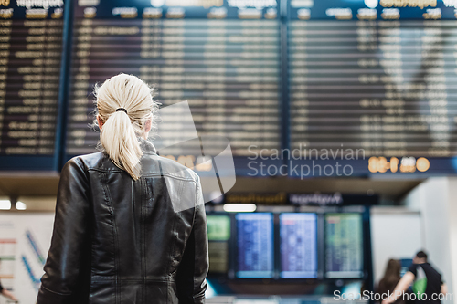 Image of Female traveller checking flight departures board.