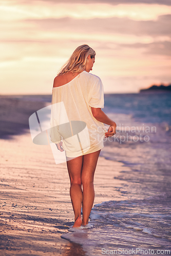 Image of Lady on sandy tropical beach at sunset.
