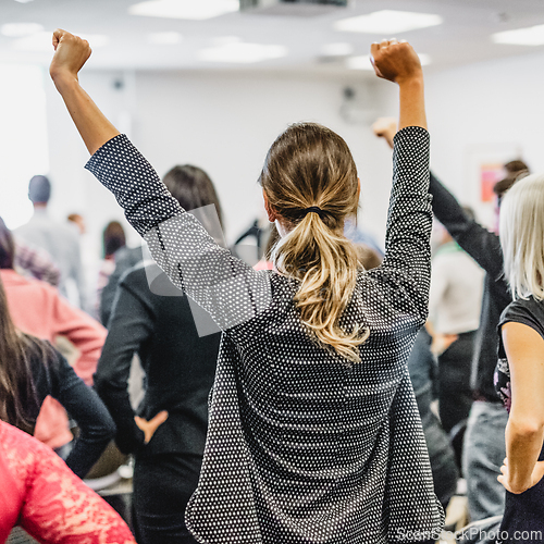 Image of Participants of interactive motivational speech feeling empowered and motivated, hands raised high in the air.