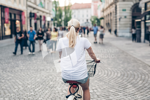 Image of Beautiful blond caucasian woman riding bike in the city center