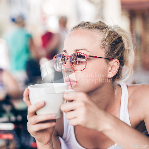 Image of Woman drinking coffee outdoor on street.